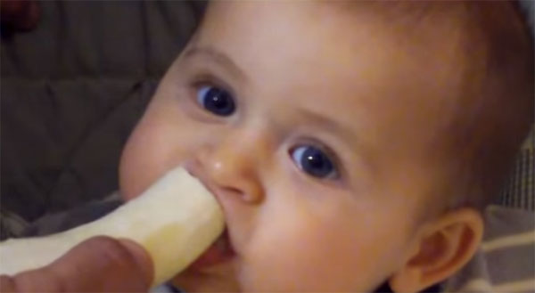 Мальчик ест банан