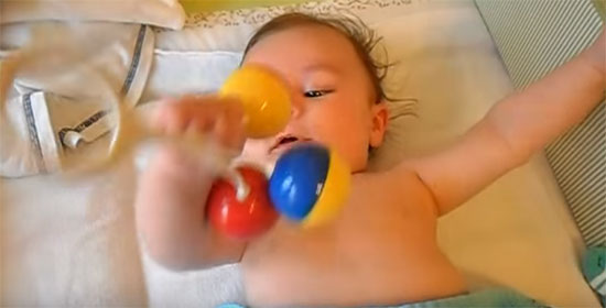 Малыш бьет себя погремушкой