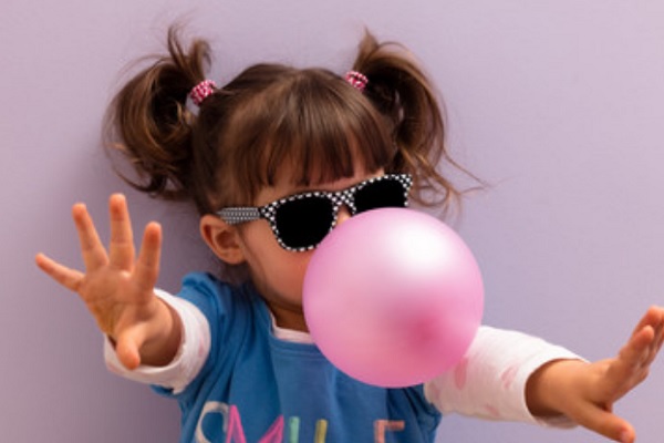 Девочка надувает пузырь из жвачки