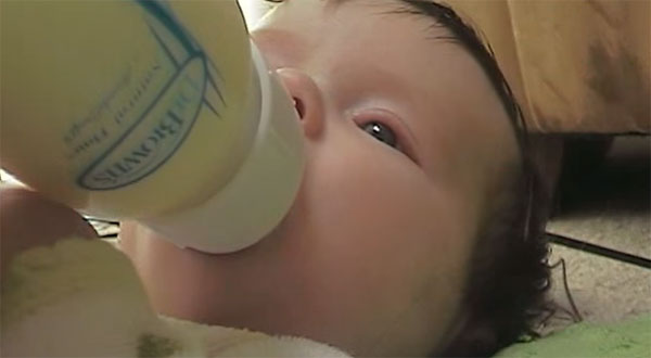 Малыш пьет молоко из бутылочки
