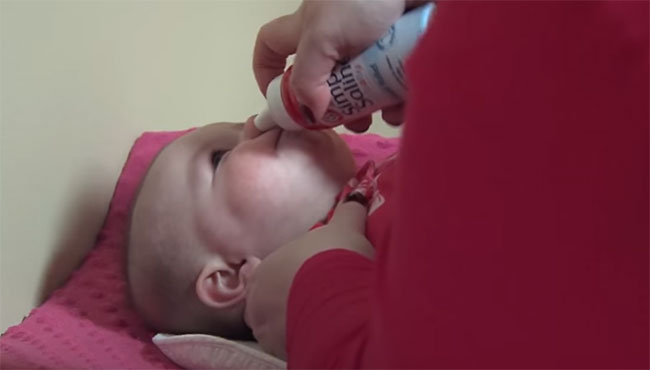 Мама капает нос ребенку