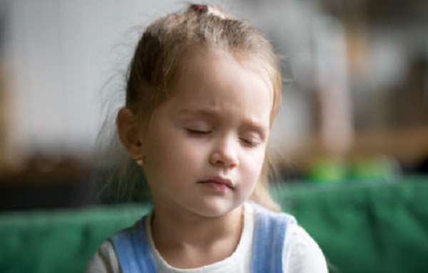 Девочка сидит с закрытыми глазами
