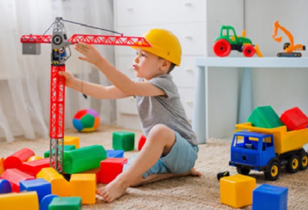Ребенок играет с краном. Рядом разбросанные кубики