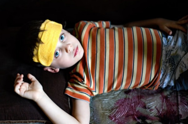 Ребенок лежит с тряпочкой на лбу