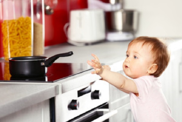 Ребенок тянется к сковороде, которая стоит на плите