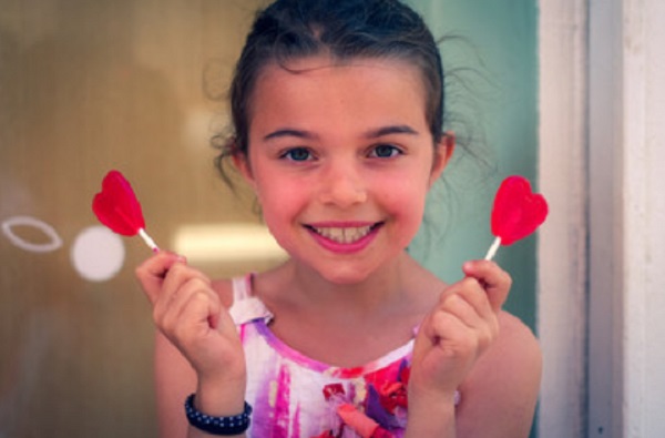 Девочка держит в руках два леденца на палочках