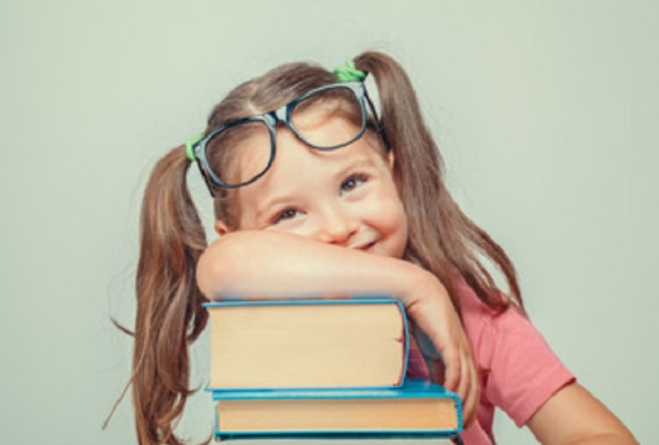 Девочка сидит возле стопки книг