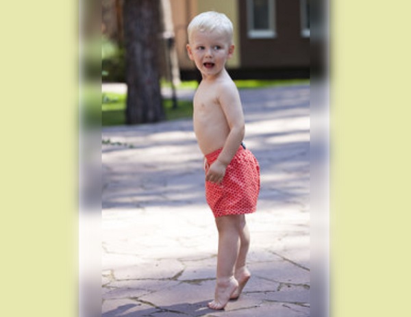 Мальчик на улице стоит на цыпочках (у него босые ноги)