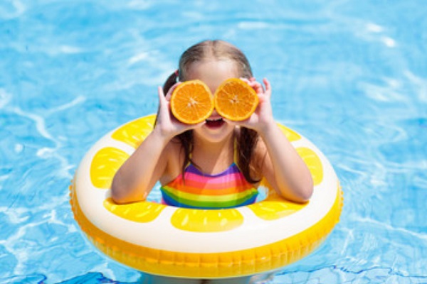 Девочка держит перед глазами кружочки апельсина