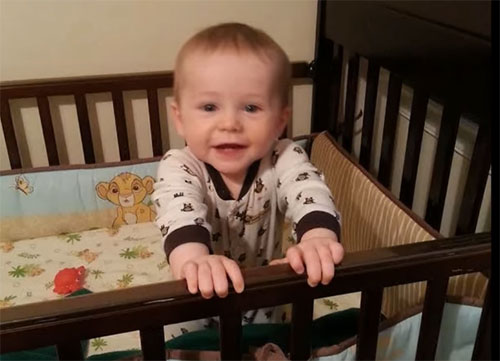 Малыш стоит в кроватке
