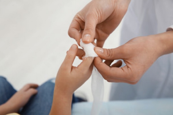 Ребенку накладывают бинт на палец
