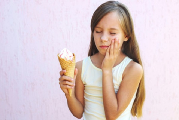 Девочка схватилась за зубы. У нее в руке мороженое