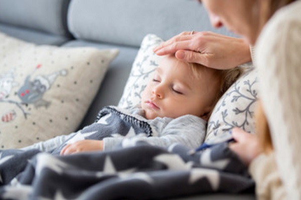 Ребенок в постели. Мама трогает его лобик