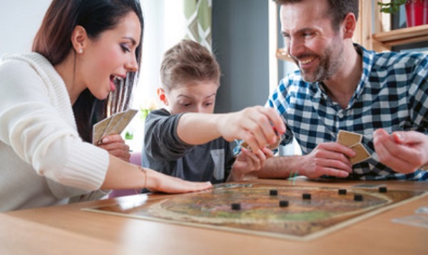 Ребенок играет с родителями в настольную игру