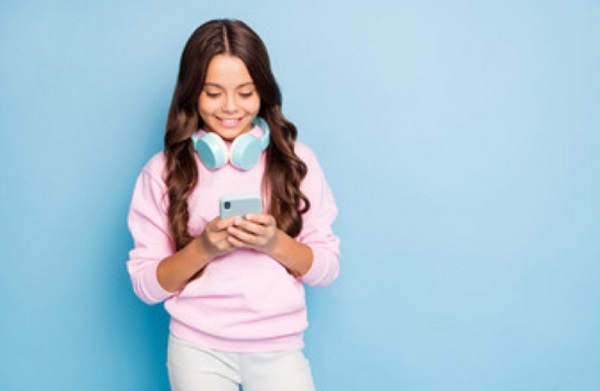 Девочка улыбается, смотря на экран телефон