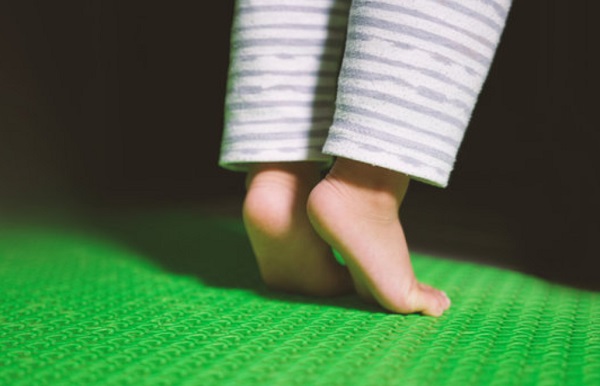 Ребенок стоит на носочках на специальном коврике