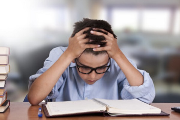 Уставший мальчик сидит над книгой