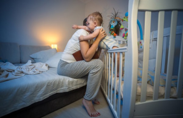 Мама достает ребенка из кроватки