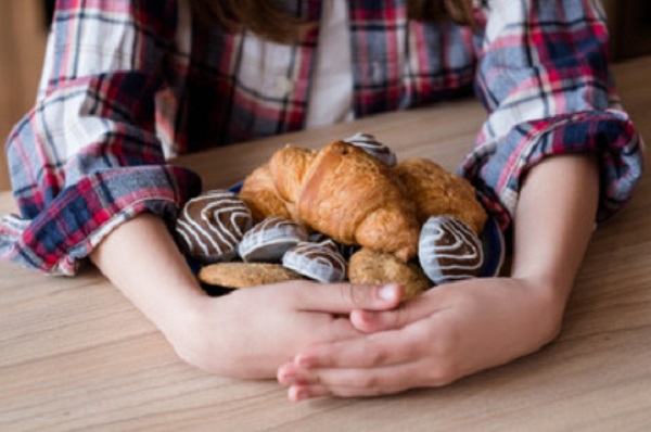 Ребенок обхватил множество сладостей