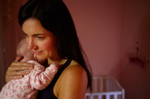 Мама держит ребенка на руках в темной комнате