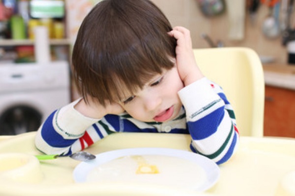 ребенок задумчиво смотрит на свою тарелку