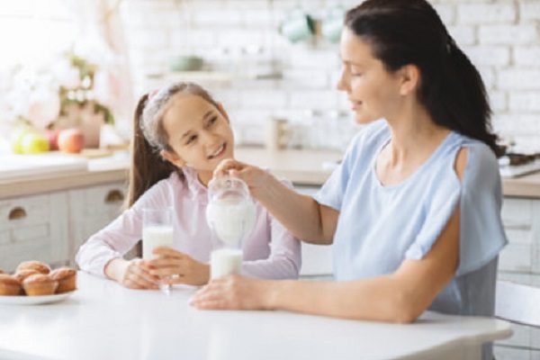 Мама наливает молоко дочери и себе