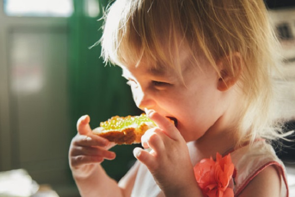 Девочка кусает бутерброд с красной икрой