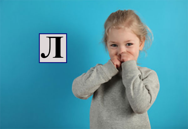 Девочка прячет рот руками. Рядом буква л