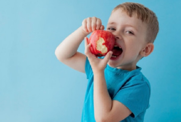 Мальчик держит в руке надкусанное яблоко