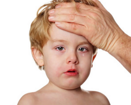 У ребенка слезятся покрасневшие глаза. Взрослый человек приложил свою руку ко лбу малыша, проверяет температуру