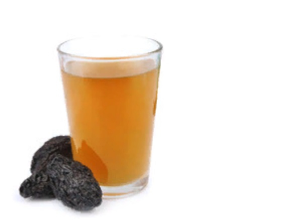 Стакан компота с черносливом. Рядом с ним лежит три чернослива