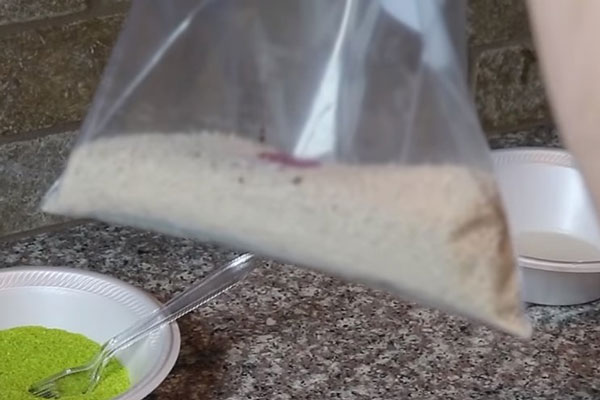 Песок насыпанный в пакет. Видно, что было добавлено несколько капель.