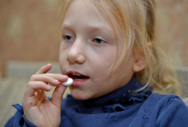 Девочка кладет таблетку в рот