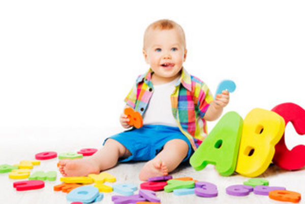 Ребенок сидит на полу. Вокруг него мягкие английские литеры