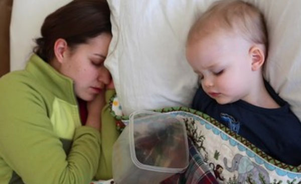 Мама спит рядом с ребенком. Возле малыша лежит емкость для возможной рвоты