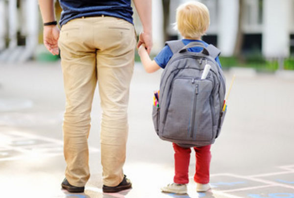 Мальчик держит папу за руку. На спине у него очень большой рюкзак