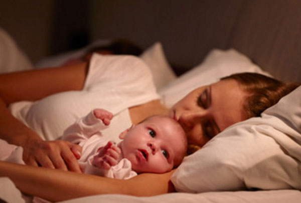 мама с грудничком в кровати. Она с закрытыми глазами, малыш - нет