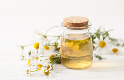 Отвар ромашки в баночке, рядом цветки растения