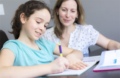 Мама смотрит за тем, как дочка пишет