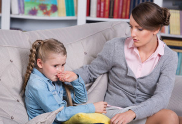 Девочка плачет, прикрывает рукой рот. Рядом сидит мама