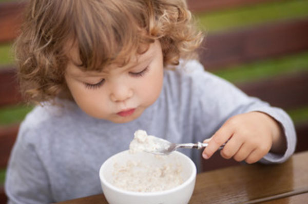 Маленький ребенок ест овсяную кашу