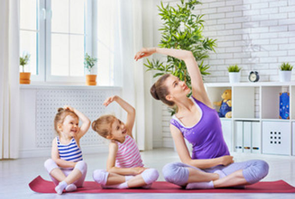Мама занимается йогой со своими маленькими дочками