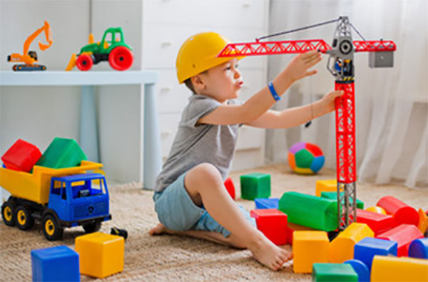 Мальчик играет на полу, рядом кубики и строительный кран