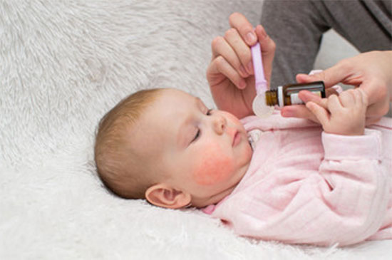 Ребенку с красными щеками в ложечку наливают лекарство