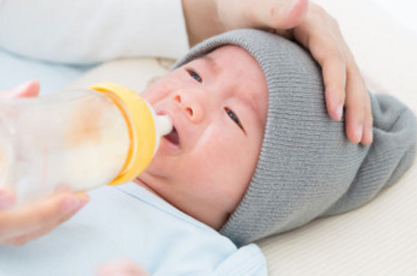 Грудной ребенок плачет. Мама пытается кормить его с бутылочки