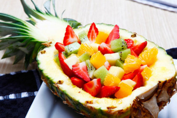 Половинка ананаса, заполненная фруктовым салатом