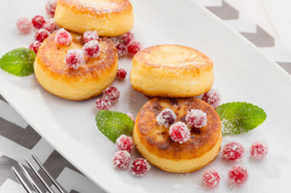 Готовые сырники, украшенные ягодами и листочками