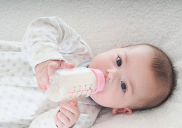 Грудной ребенок пьет из бутылочки