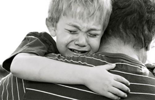 Папа несет плачущего мальчика