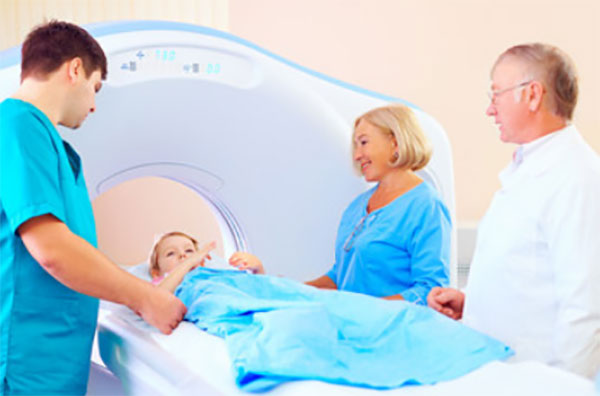 Мальчик лежит на столе МРТ. Рядом стоят врачи